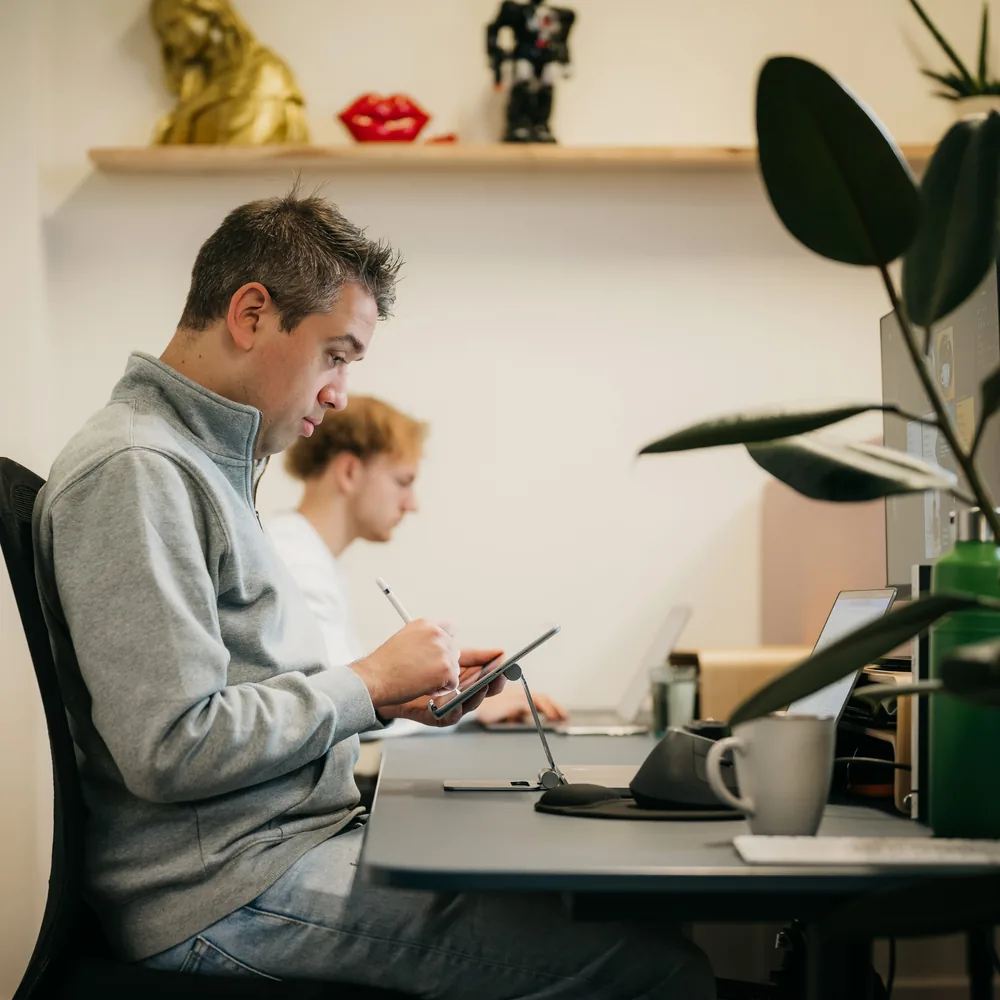 Twee collega's werken naast elkaar aan hetzelfde bureau
